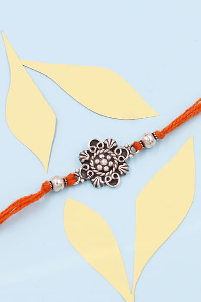 Orange and silver floral thread rakhi